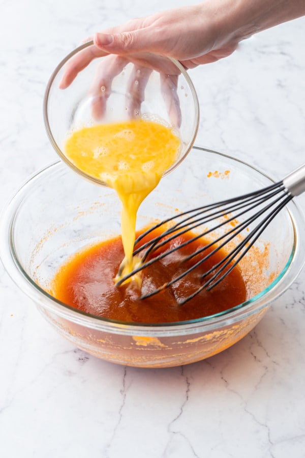 Adding lightly beaten eggs to persimmon mixture.