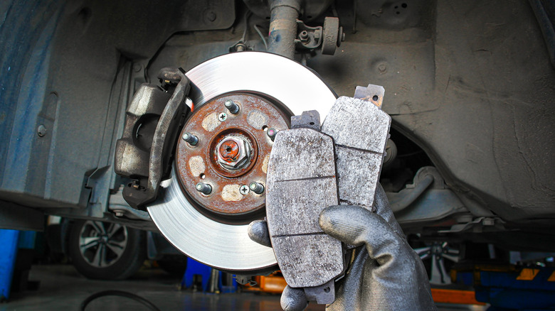Mechanic holding worn brake pads from a car's brakes